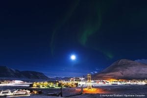 Northern Lights in darky sky above town of Longyearbyen in winter in Svalbard, Arctic Norway