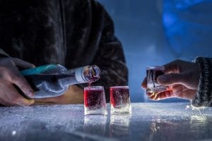 Close up of dark red shots being poured into ice shot glasses at ice bar in Arctic Norway