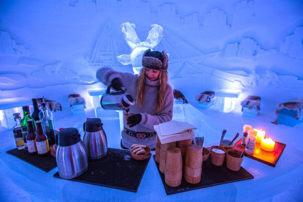 Norwegian girl pouring hot drinks behind ice bar at Ice Domes, Tromso, Norway