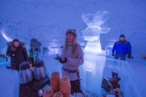 Norwegian girl smiling at customer behind ice bar at Ice Domes, Tromso, Norway