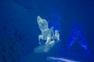 Ice dog sculpture facing forward with dark blue background inside ice domes in Arctic Norway