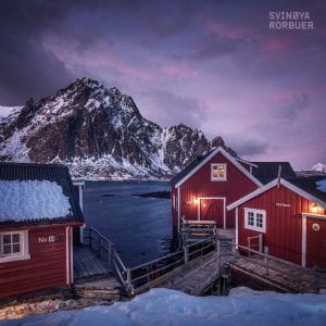 three red cabins with a mountain in the background and snow