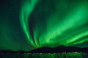 Northern Lights Aurora Borealis Green in the sky with water and fjords and trees